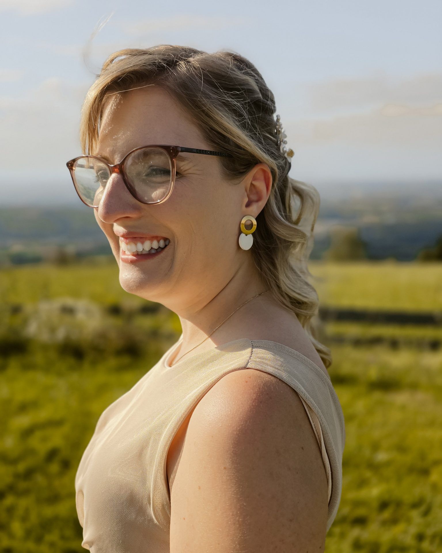 Handgemachte Keramik-Ohrringe in Weiß mit goldfarbenem Edelstahlstecker, antiallergisch, modernes Design getragen von einer Frau mit blond melierten Haaren mit Brille